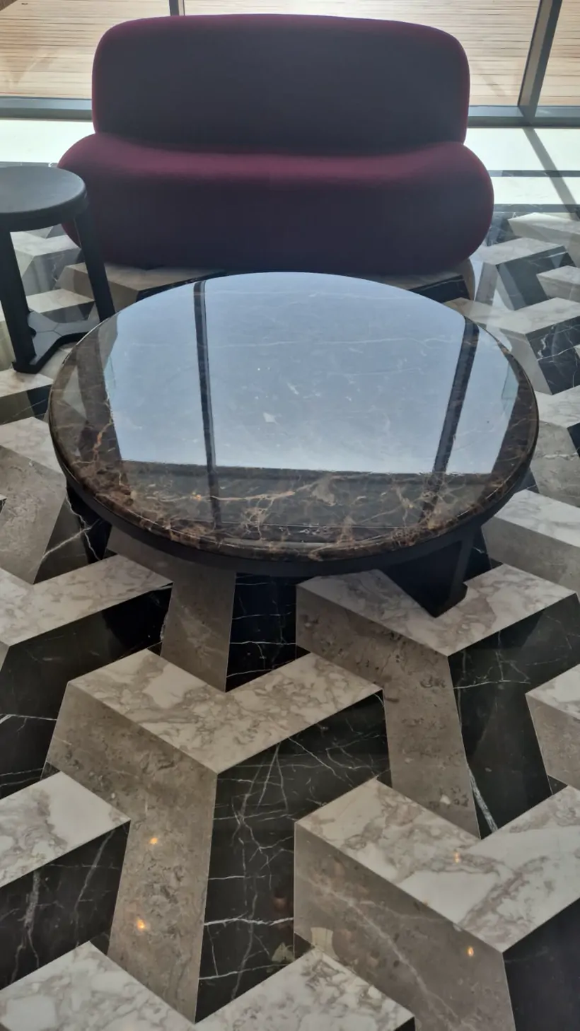 Table basse ronde en marbre Emperador protégée par un film PPF finition brillante, dans le lobby d'un hôtel